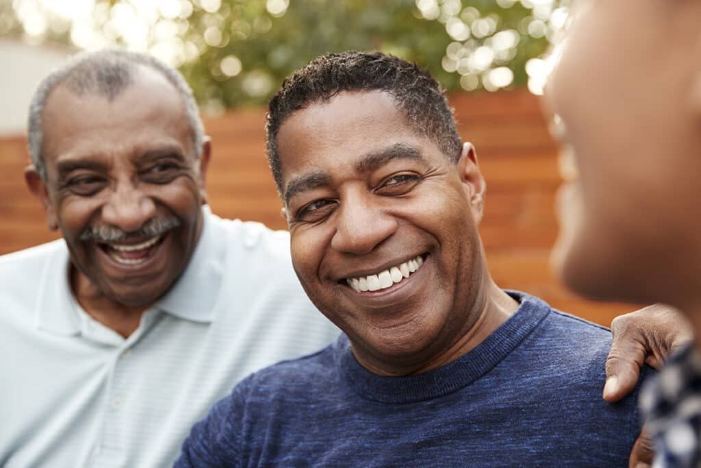 Three generations of family men laughing together, close up